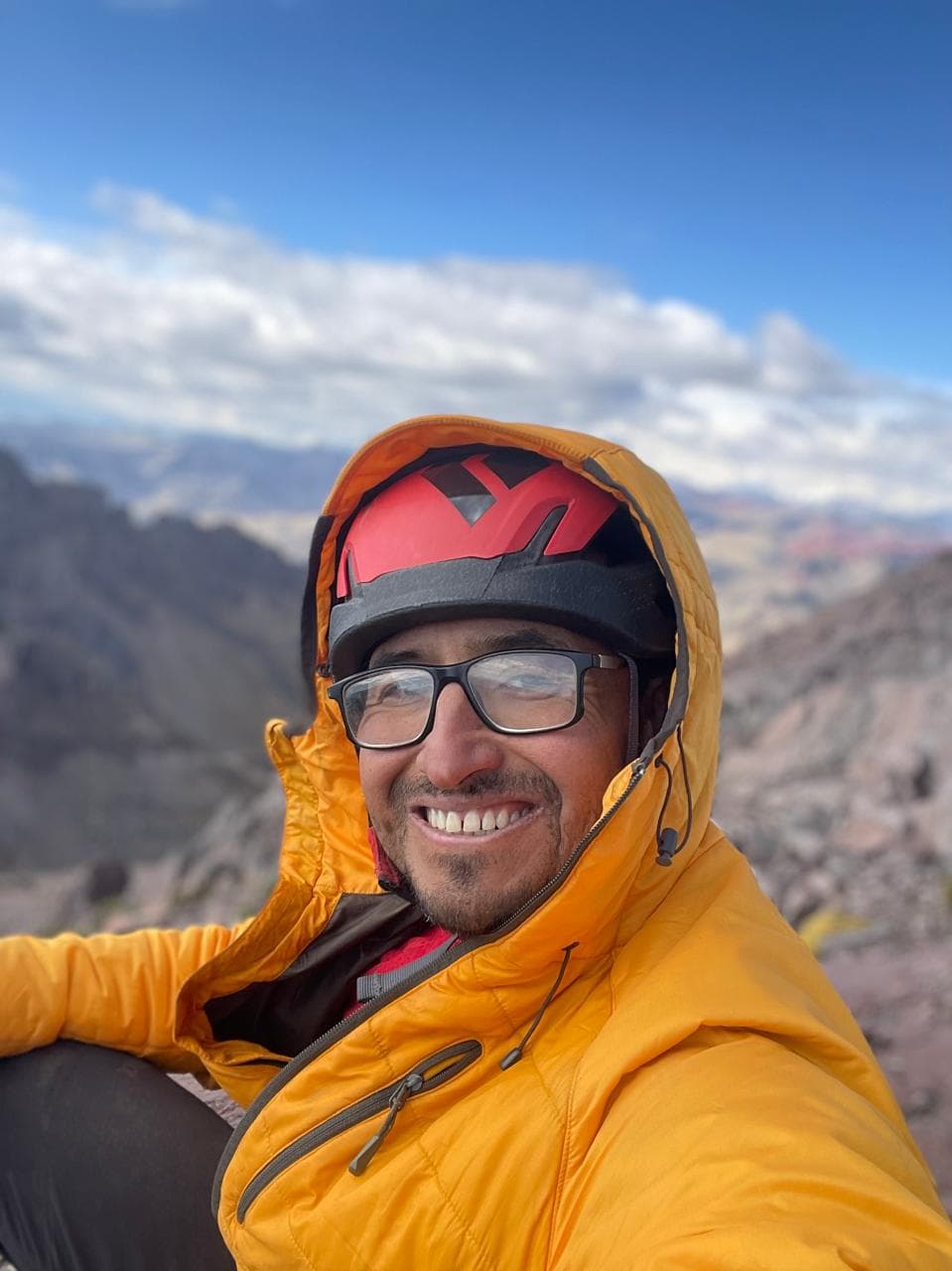 Portrait of Rodrigo Mendoza in climbing gear in the Peruvian mountains.